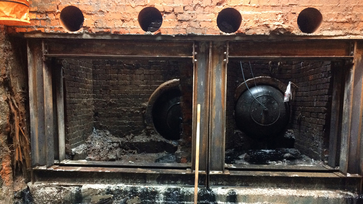 Steel frame temporary works installed to facilitate connection of existing siphon pipes to the new chamber. Holes cored for temporary ‘pin’ supports are visible in brickwork and inflatable bungs visible at back of existing chambers – Courtesy of Dawson WAM Ltd